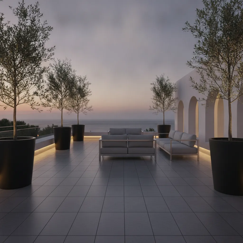 Moderne Terrasse mit großformatigen grauen Steinbelägen, minimalistischen Alu-Möbeln und formstarken Olivenbäumen in schwarzen Kübeln – klassisches zeitgenössisches Design mit subtiler LED-Beleuchtung